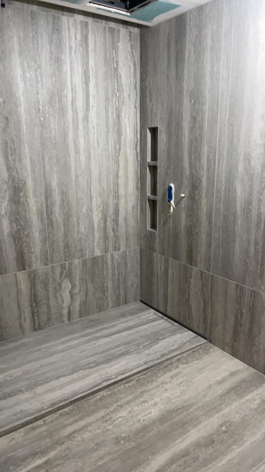 Douche de plain-pied en grès cérame très grand format effet travertin gris, caniveau linéaire et niche à trois cases, Bourg-en-Bresse