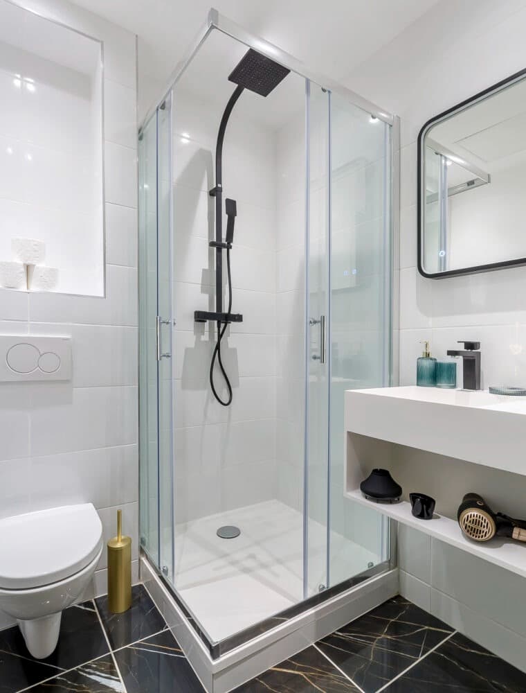 Salle de douche au sol effet marbre noir veiné doré posé en diagonale, faïence blanche brillante et WC suspendu, Vaulx-en-Velin