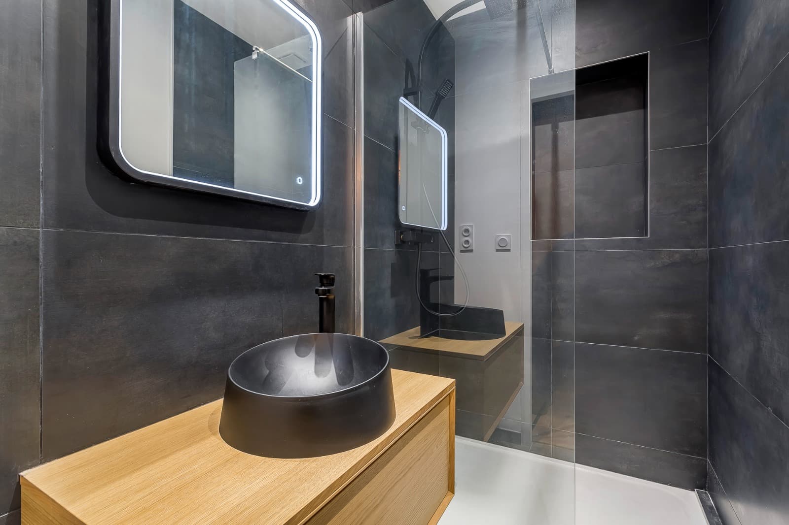 Vasque à poser noire mate sur meuble chêne, miroir LED et douche en faïence anthracite grand format avec niche, Saint-Priest